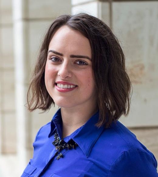 Woman with short brown hair smiling wearing a blue button up shirt 