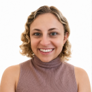 Smiling young woman with short blonde curls in mauve sleeveless turtleneck, white background
