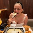 Woman with blonde hair wearing a white dress eating cheese